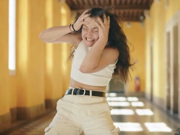Capture du clip vidéo dans lequel une élève se tient la tête dans les mains dans un grand couloir vide